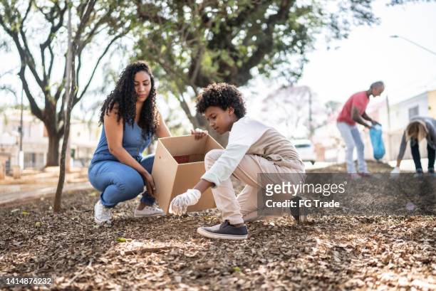 mother and son picking up garbage to clean a public park - volunteers cleaning public park stock pictures, royalty-free photos & images