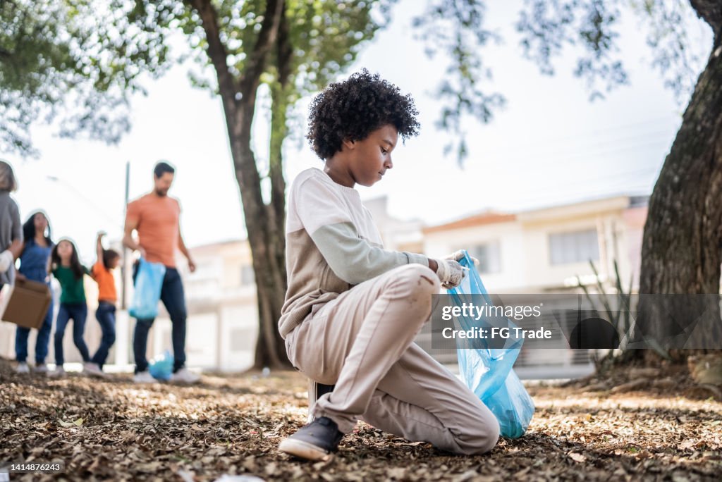 Niño recogiendo basura para limpiar un parque público