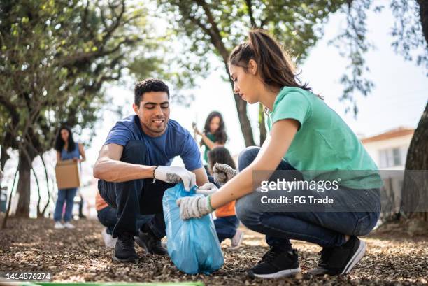 couple picking up garbage to clean a public park - plucking bildbanksfoton och bilder