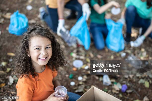 retrato de una niña recogiendo basura para limpiar un parque público - only girls fotografías e imágenes de stock