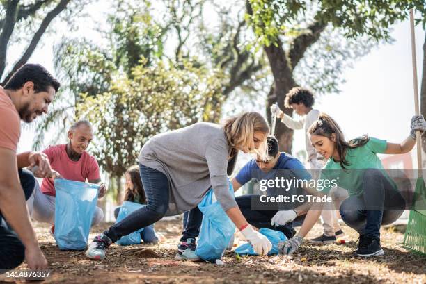 people picking up garbage to clean a public park - garbage picker stock pictures, royalty-free photos & images