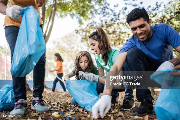 people picking up garbage to clean a public park - limpeza ambiental imagens e fotografias de stock
