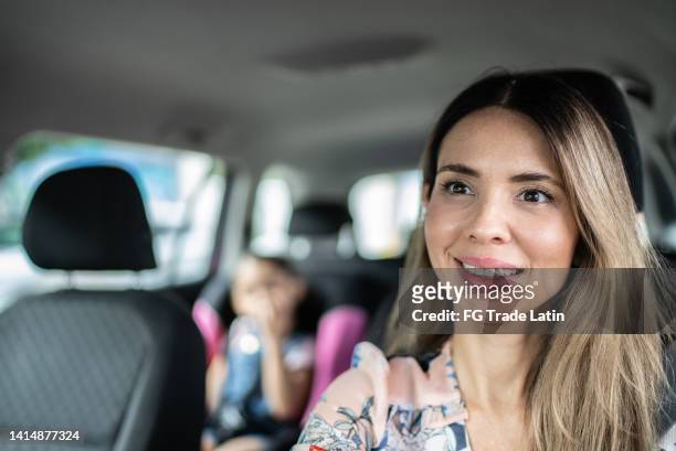 mulher dirigindo e conversando com filha criança estudante no carro - family inside car - fotografias e filmes do acervo