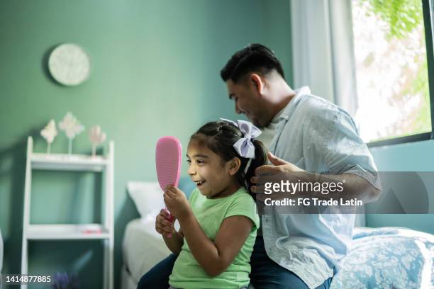 father combing daughter's hair at home - man combing hair stock pictures, royalty-free photos & images