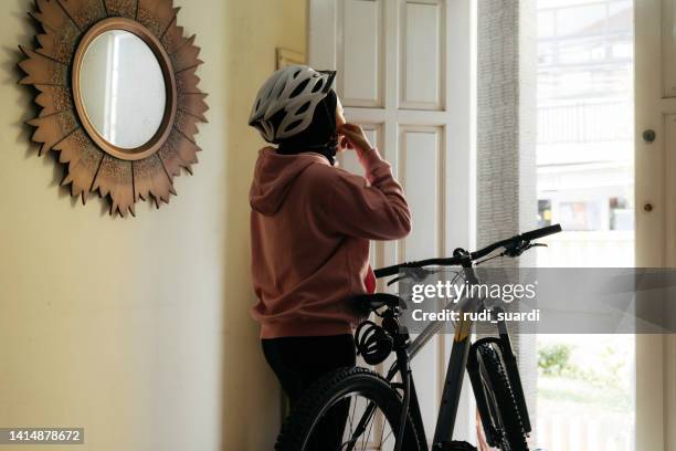 muslim woman putting on helmet at home - crash helmet stock pictures, royalty-free photos & images