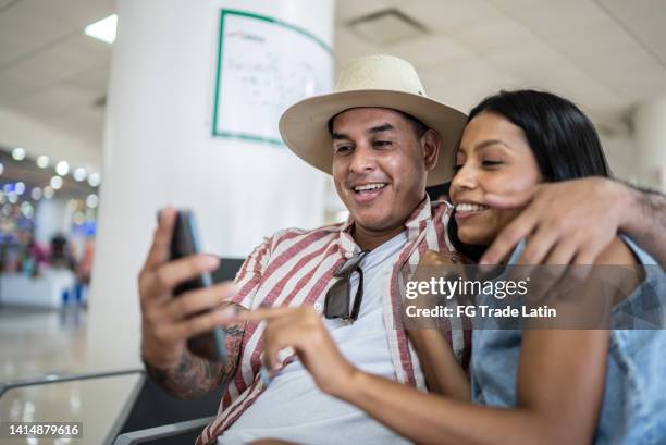 couple using mobile phone while waiting for boarding in the departure at airport - board game stockfoto's en -beelden