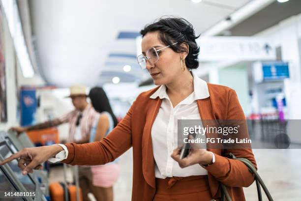 mujer de negocios haciendo check-in en el aeropuerto - tótem fotografías e imágenes de stock