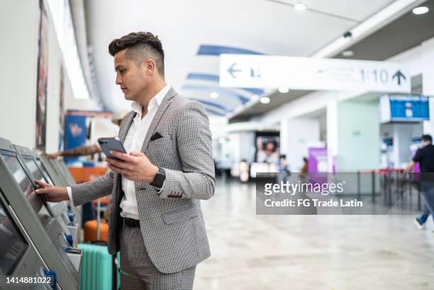 businessman doing check-in and using phone at the airport - totem imagens e fotografias de stock