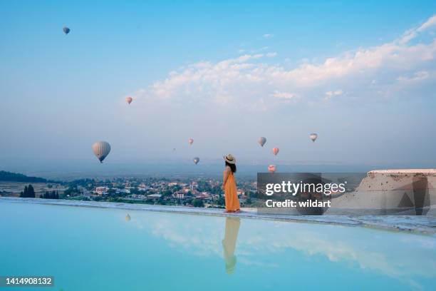 beautiful traveller tourist girl is  watching hot air balloons in pamukkale travertine pools in  denizli, turkey - pamukkale stock pictures, royalty-free photos & images