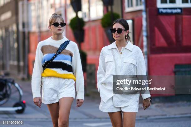 Guest wears black sunglasses, gold earrings, a white / brown / blue / black / yellow striped print pattern / ripped wool pullover, a black shiny...