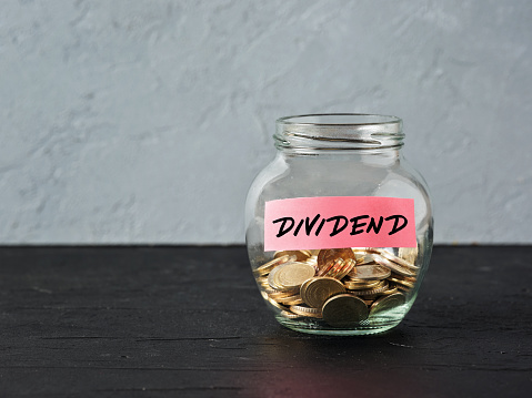 Glass jar with coins and the word dividend on a label. Business finance investment, distribution of profits or dividend tax