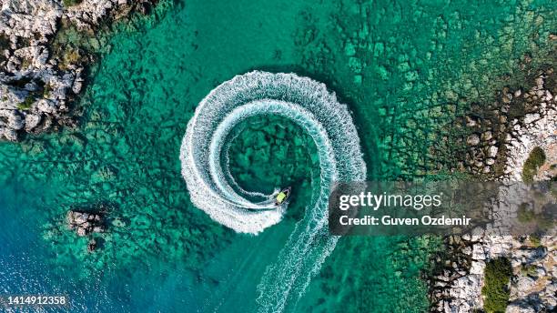 zoom arrière vue aérienne étonnante d’un homme conduisant une motomarine dans l’océan créant un motif circulaire droit vers le bas, fond d’été étonnant, couleur de l’eau et belle journée d’aventure turquoise claire sur la plage tropicale - noeud coulant en huit photos et images de collection