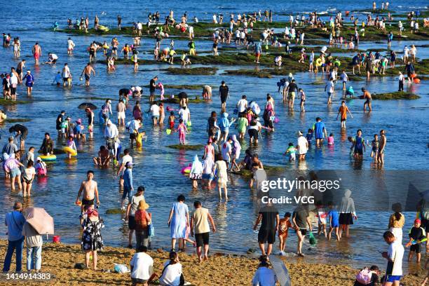 Tourists crowd at a bathing beach to cool off in hot weather on August 13, 2022 in Dalian, Liaoning Province of China.