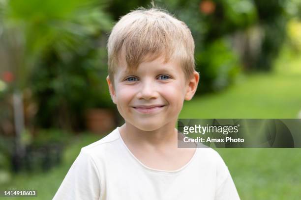 portrait of young boy in backyard. 7 years old kid looking at camera and smiling - 6 7 years stock pictures, royalty-free photos & images