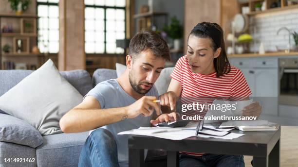 frustrated concerned young couple calculating overspend budget, doing paperwork job at laptop, talking about financial problems, insurance, mortgage, fees, loan conditions, bankruptcy, economic inflation - broken calculator stock pictures, royalty-free photos & images