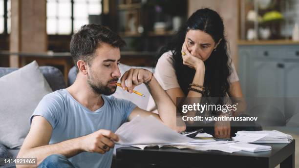 frustrated concerned young couple calculating overspend budget, doing paperwork job at laptop, talking about financial problems, insurance, mortgage, fees, loan conditions, bankruptcy, economic inflation - broken calculator stock pictures, royalty-free photos & images