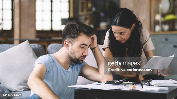 frustrated concerned young couple calculating overspend budget, doing paperwork job at laptop, talking about financial problems, insurance, mortgage, fees, loan conditions, bankruptcy, economic inflation - broken calculator stock pictures, royalty-free photos & images