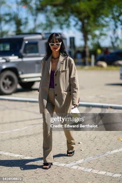 Pornwika Spiecker wears white sunglasses from Prada, a black large chain necklace from Dior, a brown striped print pattern blazer jacket, matching...