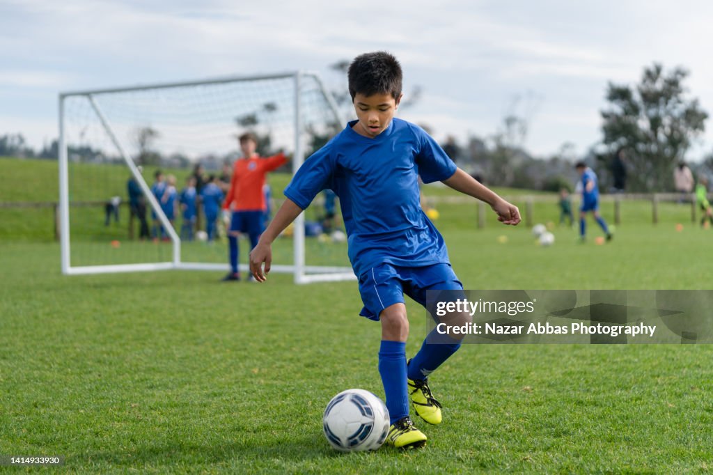 Kid in field playing soccer game.