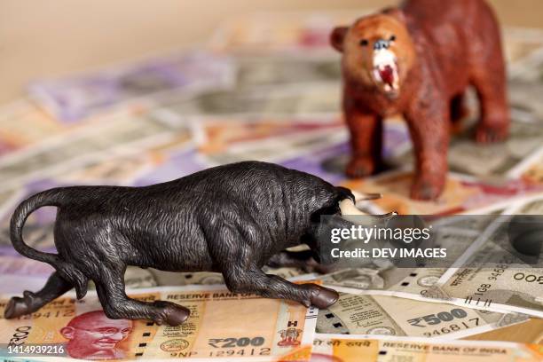 bear and bull figurines on indian currency notes - börsenbaisse stock-fotos und bilder