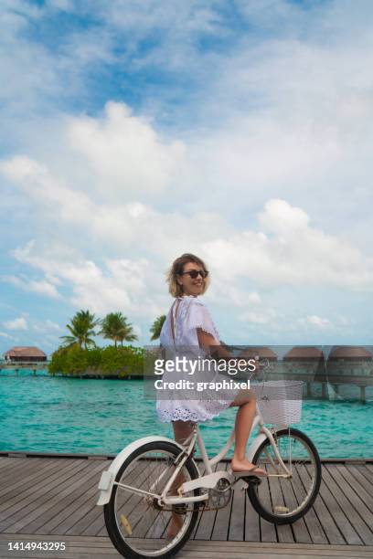 schöne frau posiert mit fahrrad auf holzsteg auf den malediven - sommerkleid stock-fotos und bilder