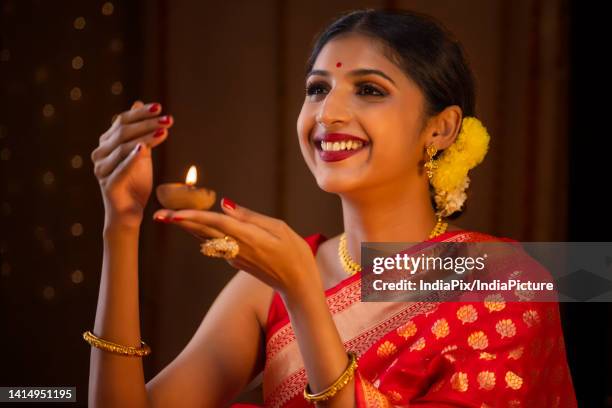close-up of a woman in red sari holding diya in her hand on the occasion of diwali - diya oil lamp fotografías e imágenes de stock