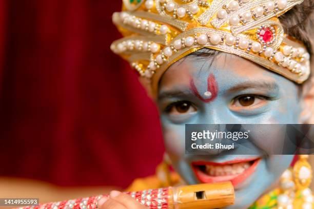 imagen en primer plano de un lindo niño indio vestido con el vestido del señor krishna y tocando la flauta. - krishna janmashtami fotografías e imágenes de stock
