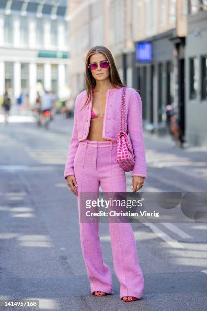 Nina Sandbech is seen wearing pink cropped jacket, pants, Chanel bag, bikini top, sunglasses, red heels on August 12, 2022 in Copenhagen, Denmark.