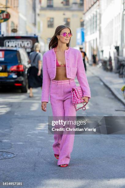 Nina Sandbech is seen wearing pink cropped jacket, pants, Chanel bag, bikini top, sunglasses, red heels on August 12, 2022 in Copenhagen, Denmark.