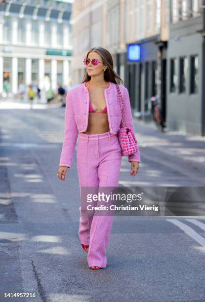 Nina Sandbech is seen wearing pink cropped jacket, pants, Chanel bag, bikini top, sunglasses, red heels on August 12, 2022 in Copenhagen, Denmark.