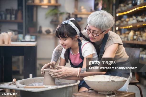 a girl is playing with clay and making pottery with her mother. - mother child clay stock-fotos und bilder