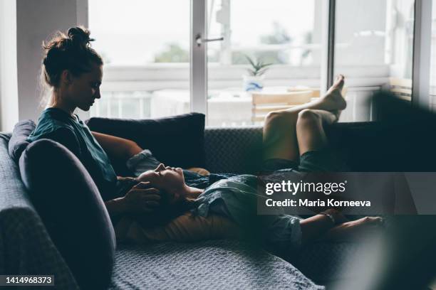 female couple enjoying time together on a sofa. - baisers lesbiennes photos et images de collection