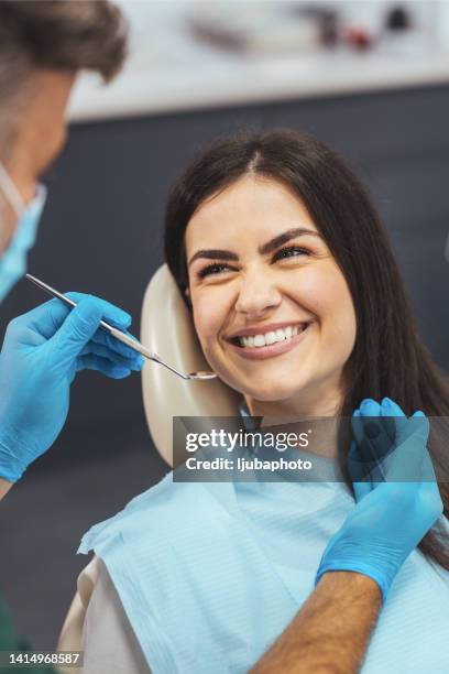 junge glückliche frau während des zahnärztlichen eingriffs in der zahnarztpraxis. - zahnarzt stock-fotos und bilder