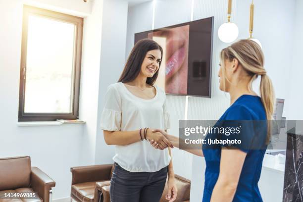 estetista che stringe la mano alla sua cliente femminile alla reception della clinica - health spa foto e immagini stock