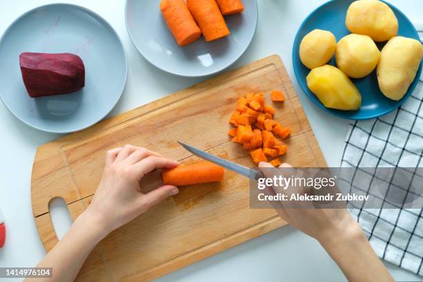 a woman cook cuts boiled carrots into cubes. preparation of a vegetable salad called vinaigrette. the concept of vegetarian and vegan food. cooking at home. home life. ethical consumption. sustainable development. vegetable food. a simple life. - gekookte aardappel stockfoto's en -beelden