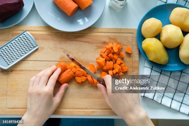 a woman cook cuts boiled carrots into cubes. preparation of a vegetable salad called vinaigrette. the concept of vegetarian and vegan food. cooking at home. home life. ethical consumption. sustainable development. vegetable food. a simple life. - gekookte aardappel stockfoto's en -beelden
