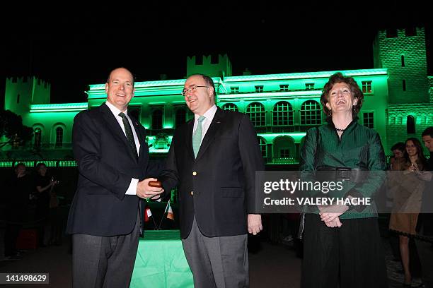 Prince Albert II of Monaco illuminates in green the Monaco's palace as he stands next to Ireland's ambassador to France Paul Kavanagh and his wife...