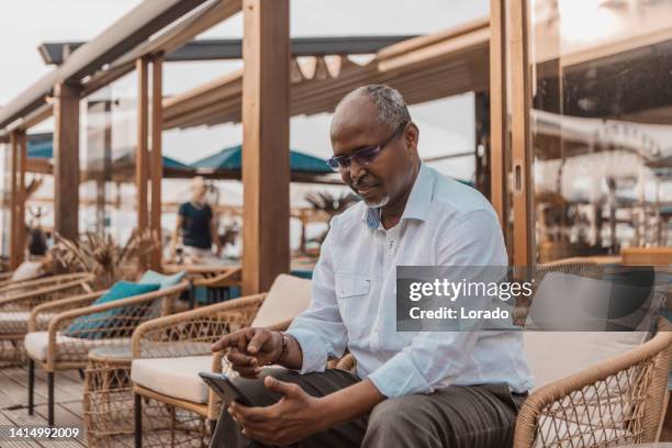 portrait of handsome senior african man looking at his device - somali man stock pictures, royalty-free photos & images
