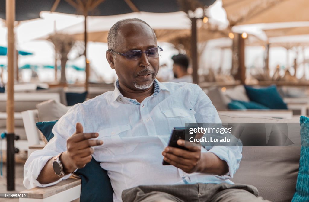 Portrait of handsome senior african man looking at his device