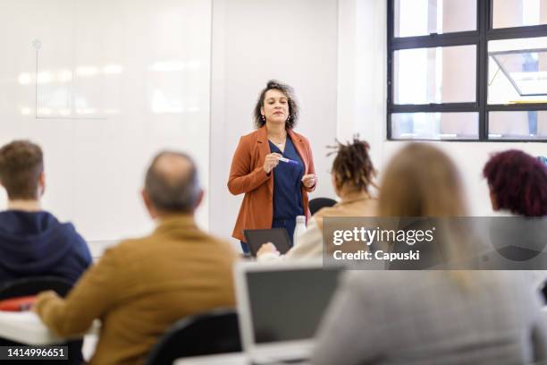 professor teaching in a full classroom - vol fysieke beschrijving stockfoto's en -beelden