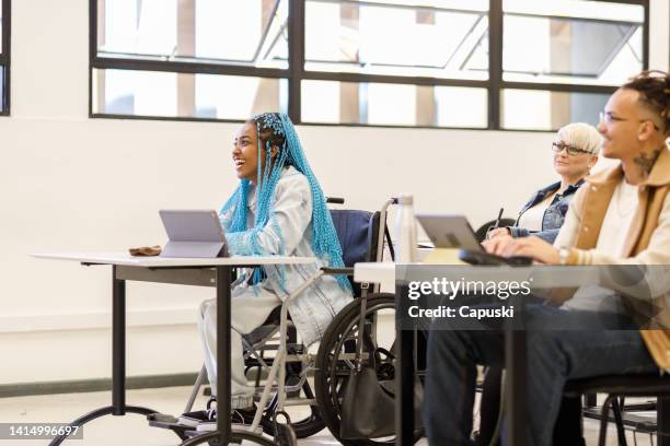 student in a wheelchair enjoying learning in class - toegang-voor-gehandicapten stockfoto's en -beelden