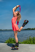 young sports trainer with beautiful legs in a pink dress jumps on spring shoes near the lake.