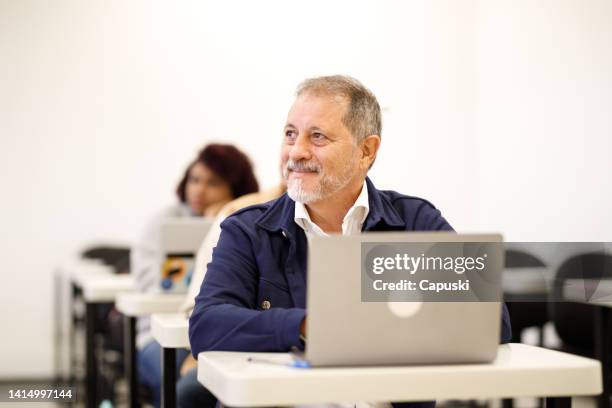 midle aged man with a laptop paying attention to class - 20 to 35 year old in class stock pictures, royalty-free photos & images