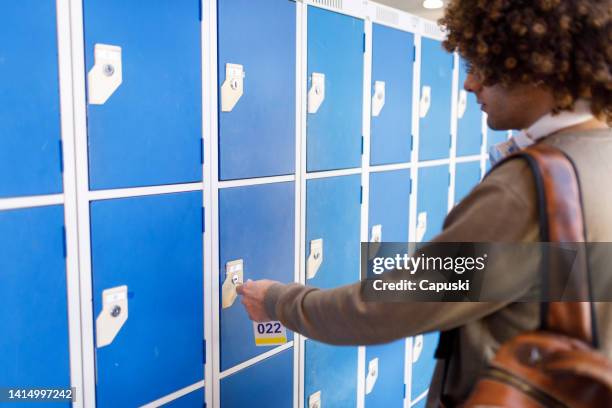 student opening a locker with key at university - campus safety stock pictures, royalty-free photos & images