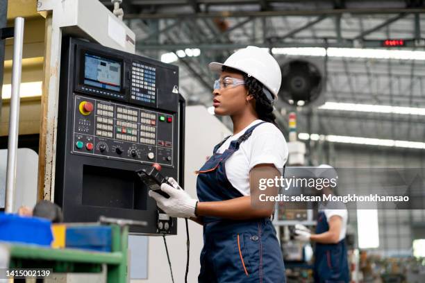 technician woman inspecting cnc machines controlled manufacturing with computer industrial - funktionskleidung stock-fotos und bilder