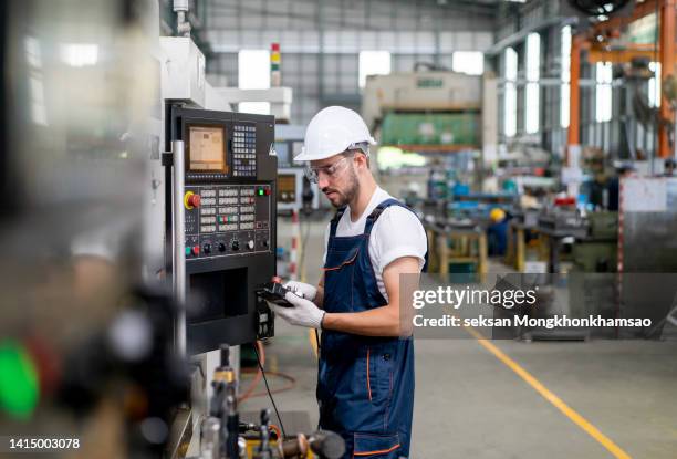 male apprentice engineer working with cnc machine in factory - operational technology fotografías e imágenes de stock