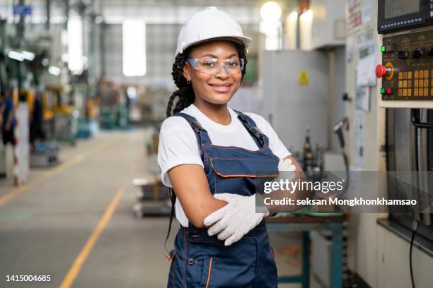 portrait of engineer standing in front of metal lathe machine in the metal parts manufacturing factory. - african american mechanic stock-fotos und bilder