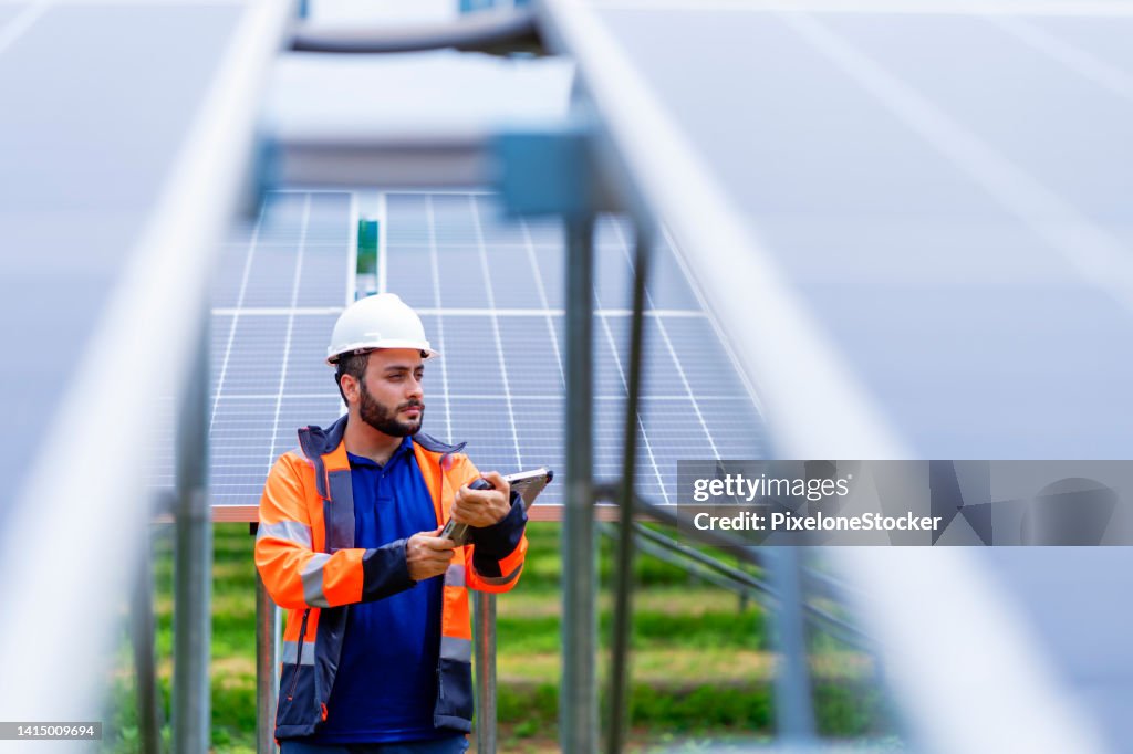 Engineer working at Solar Farm using tablet computer verify completeness of installation work.