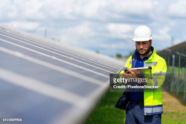 engineer working at solar farm using tablet computer verify completeness of installation work. - inspectors stock pictures, royalty-free photos & images