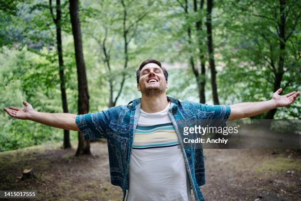 joven abrazando el aire fresco de la mañana mientras camina por el bosque - inhaling fotografías e imágenes de stock